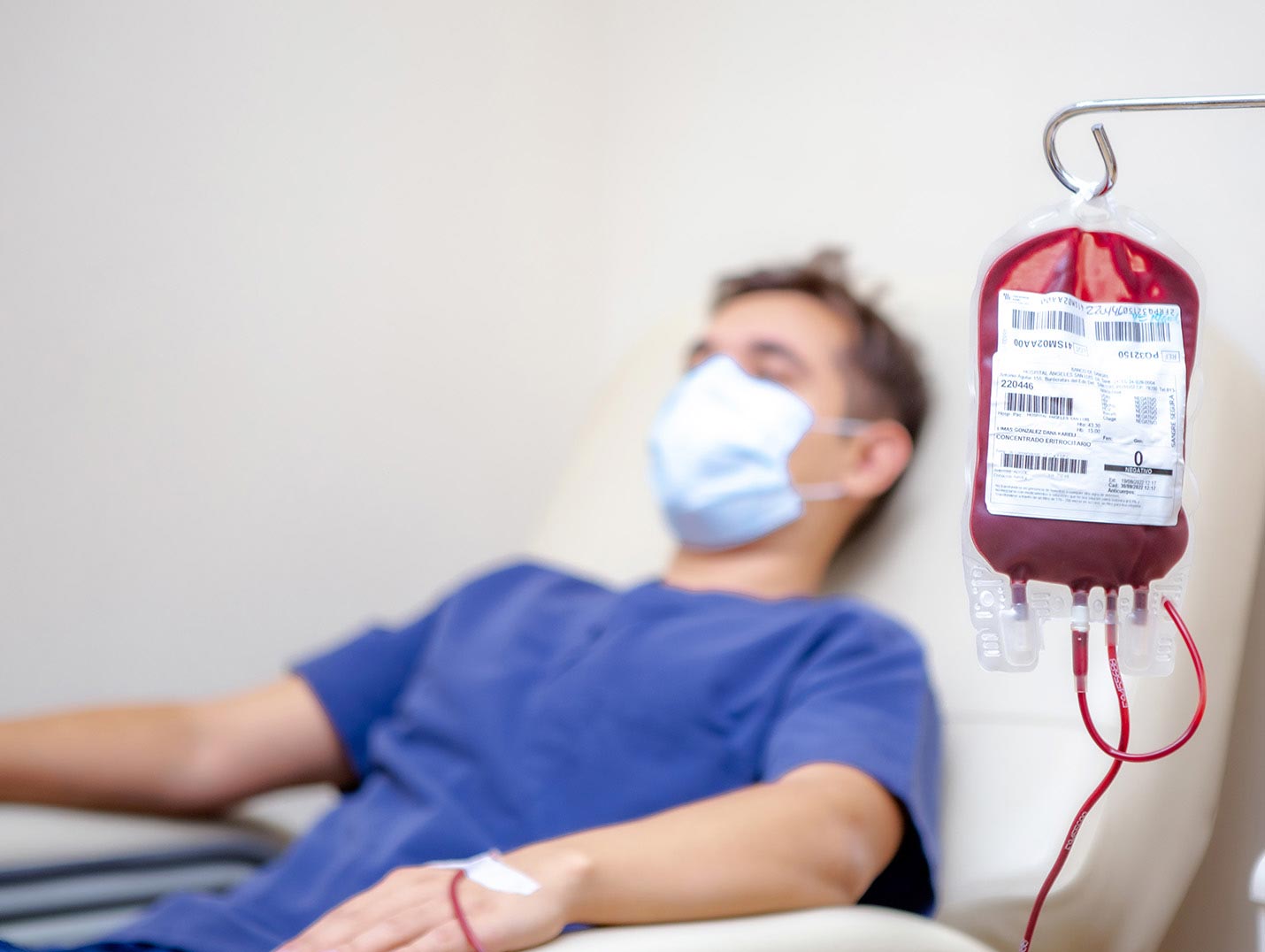 Paciente recostado sobre un sillón donando sangre y a su lado una bolsa de transfusión sanguínea en un porta suero.