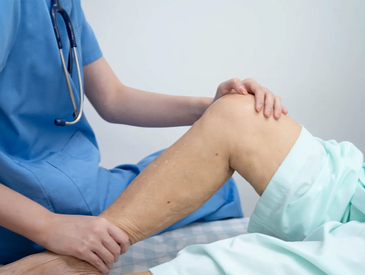 Un especialista con ropa médica azul de Hospital Angeles le da tratamiento a un paciente en el Centro de Cirugía Articular con un enfoque integral.