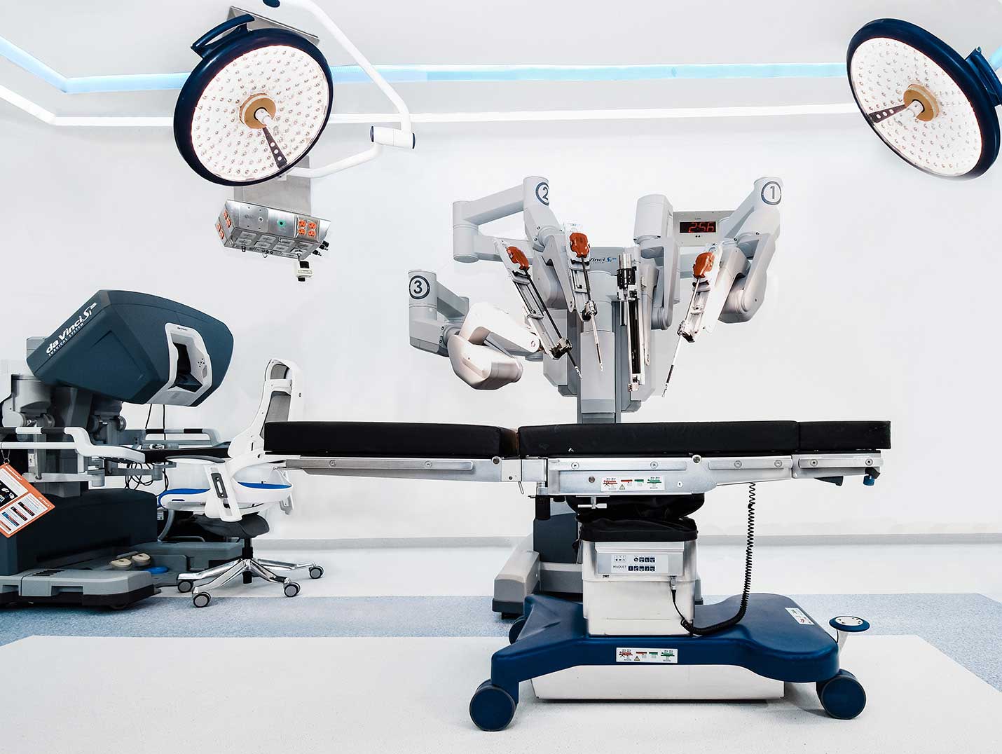 Asistente quirúrgico Da Vinci, con tres brazos mecánicos, camilla quirúrgica, dos lámparas LED y un centro de control