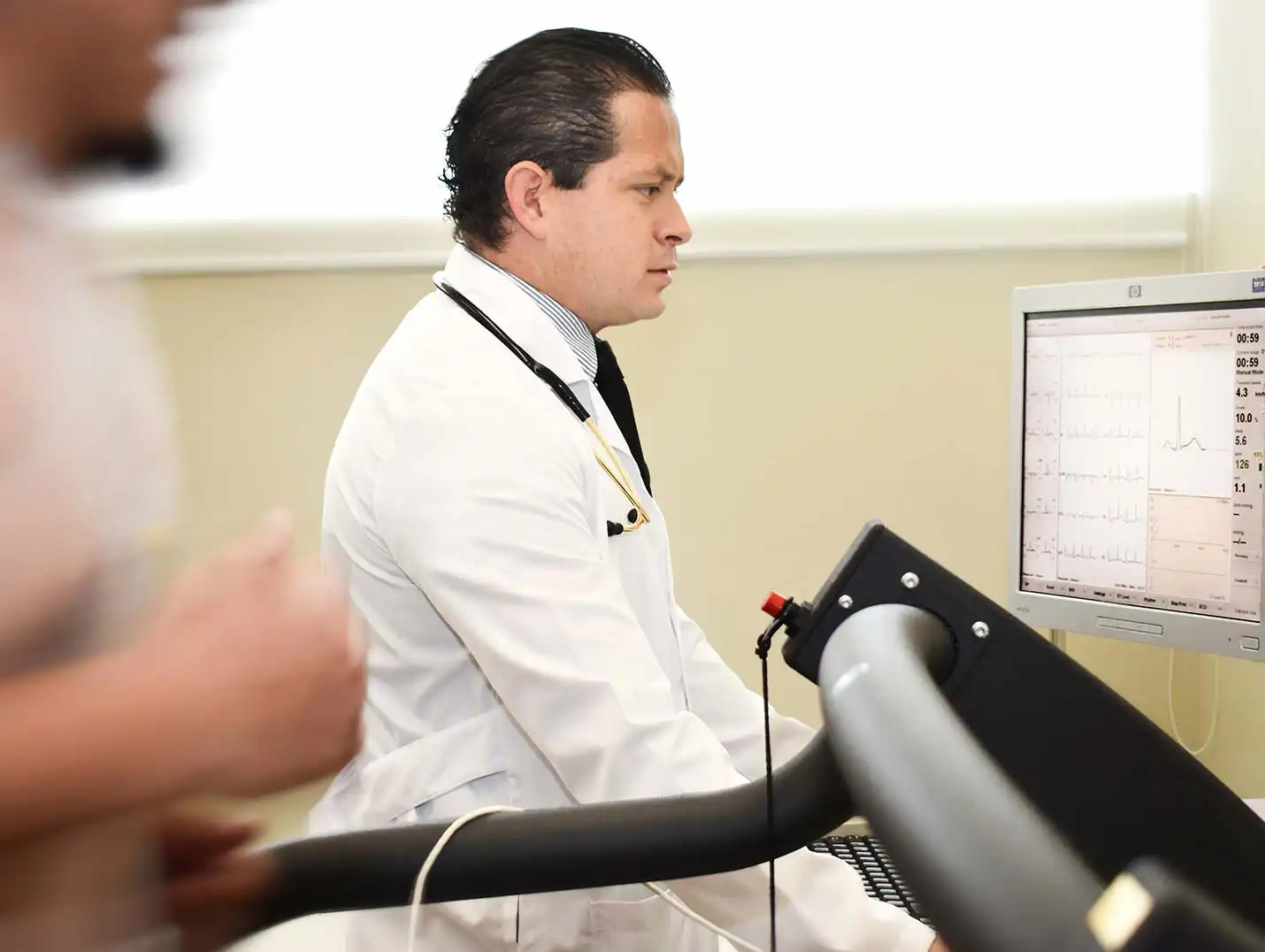 Paciente corriendo en una caminadora para un estudio de check up, siendo monitoreado por el médico