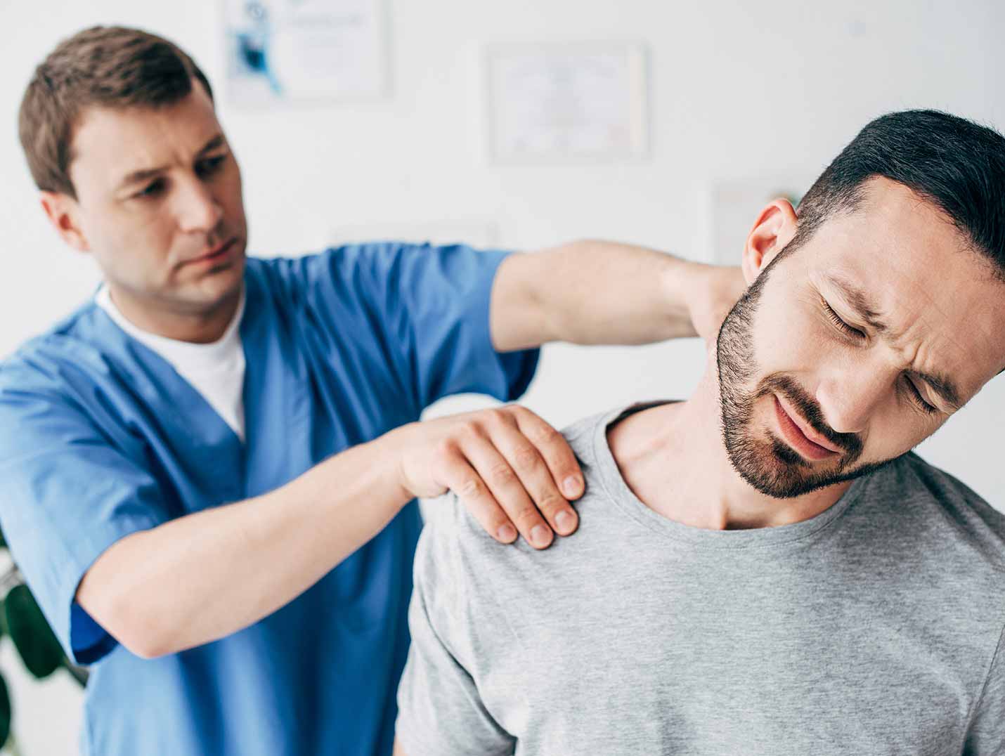 Fisioterapeuta colocando sus manos en el hombro y cuello de un paciente que se está quejando de dolor