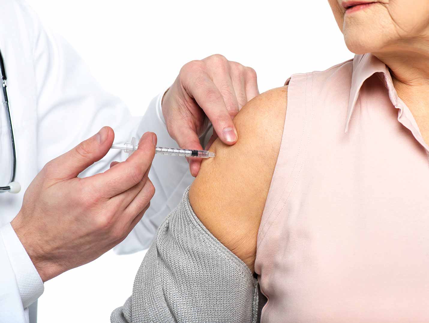 Médico aplicando una vacuna en el brazo derecho a paciente de la tercera edad