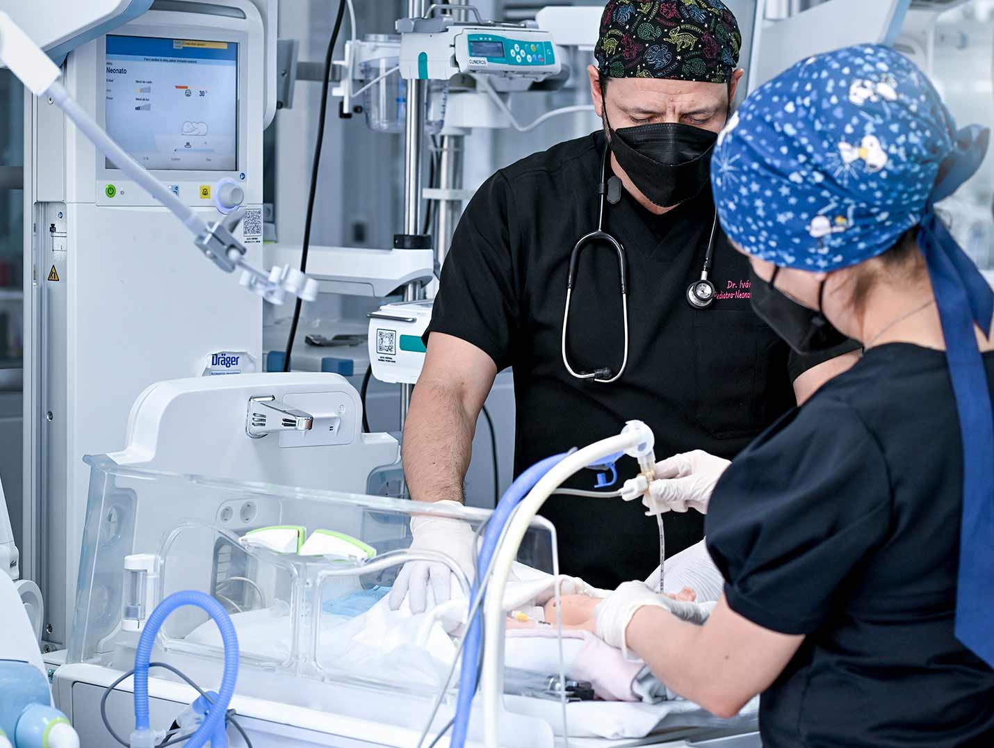 Médicos con pijamas quirúrgicas negras realizando una revisión a un bebé dentro del área de neonatología.