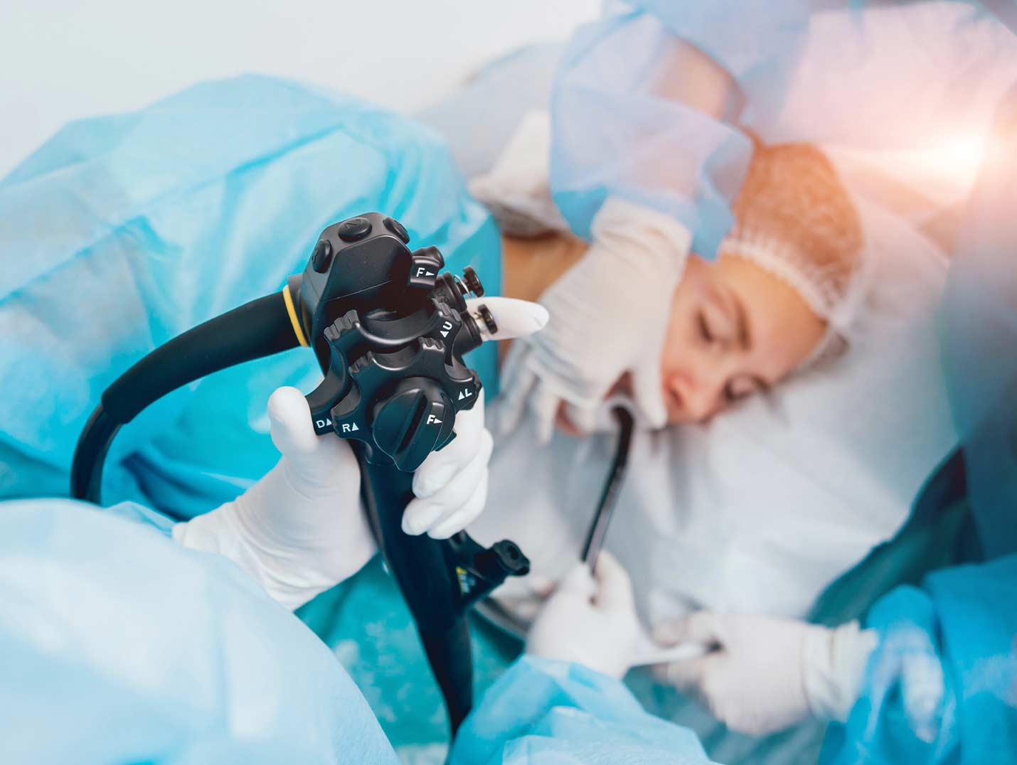 Paciente anestesiada y acostada en una mesa de exploración mientras dos médicos le realizan una endoscopia digestiva