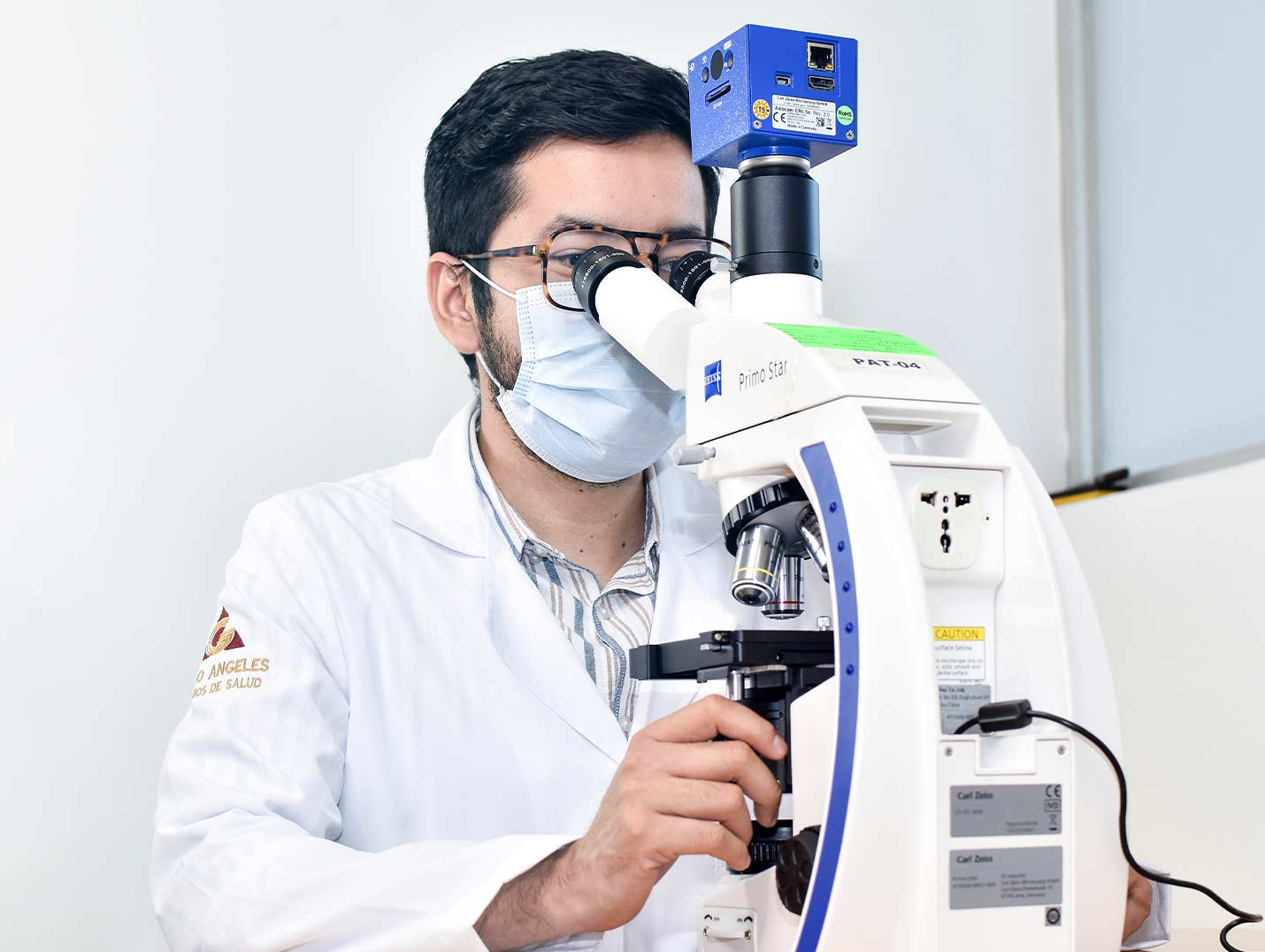 Médico de Hospital Angeles analizando una muestra de laboratorio con un microscopio