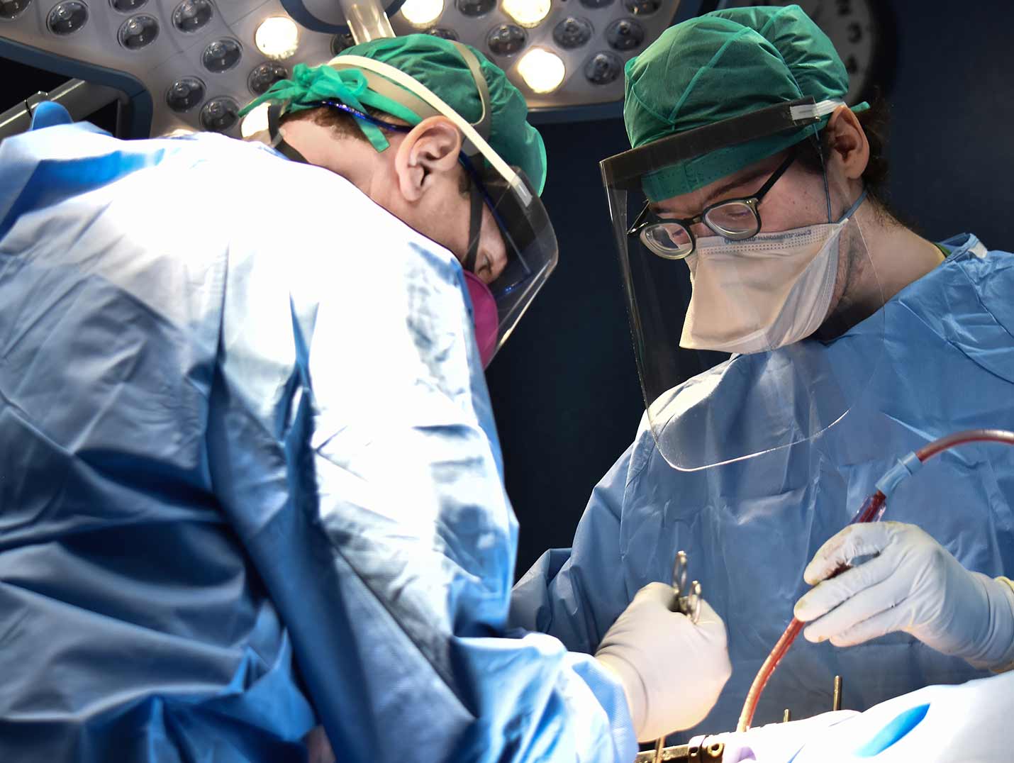 Cirujanos con batas azules y guantes blancos dentro de un quirófano durante un procedimiento de donación de órganos.