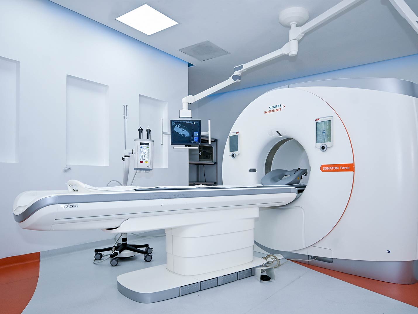 Equipo de tomografía de color blanco colocado en un cuarto de color gris con azul. 