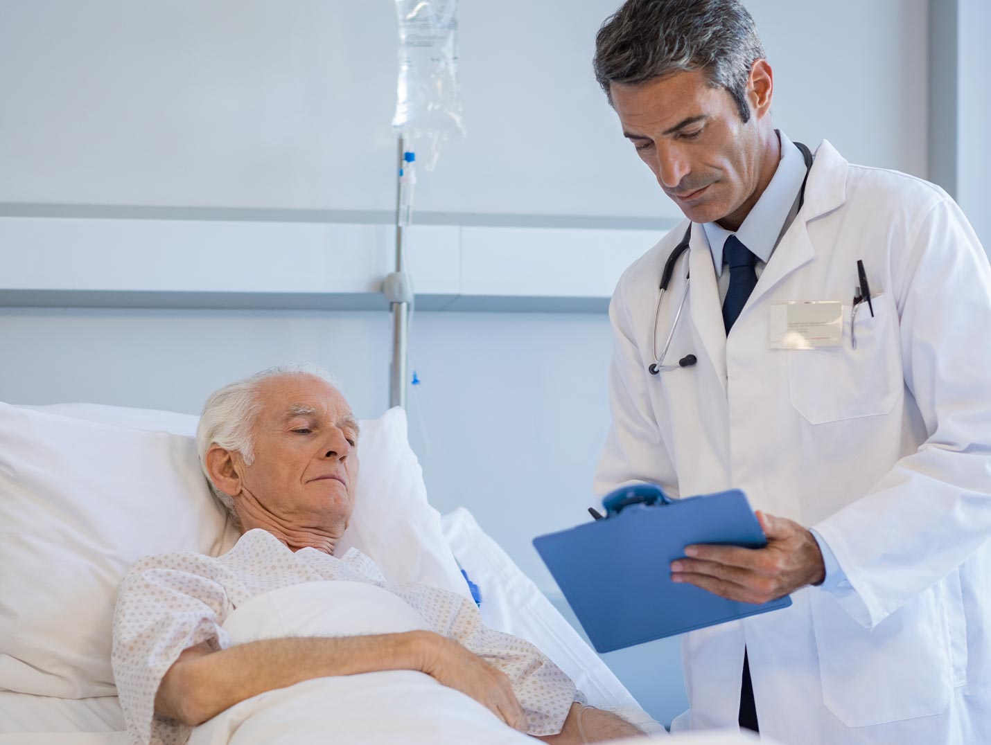Doctor con bata blanca dando un diagnóstico a una persona de la tercera edad que se encuentra internado en el hospital