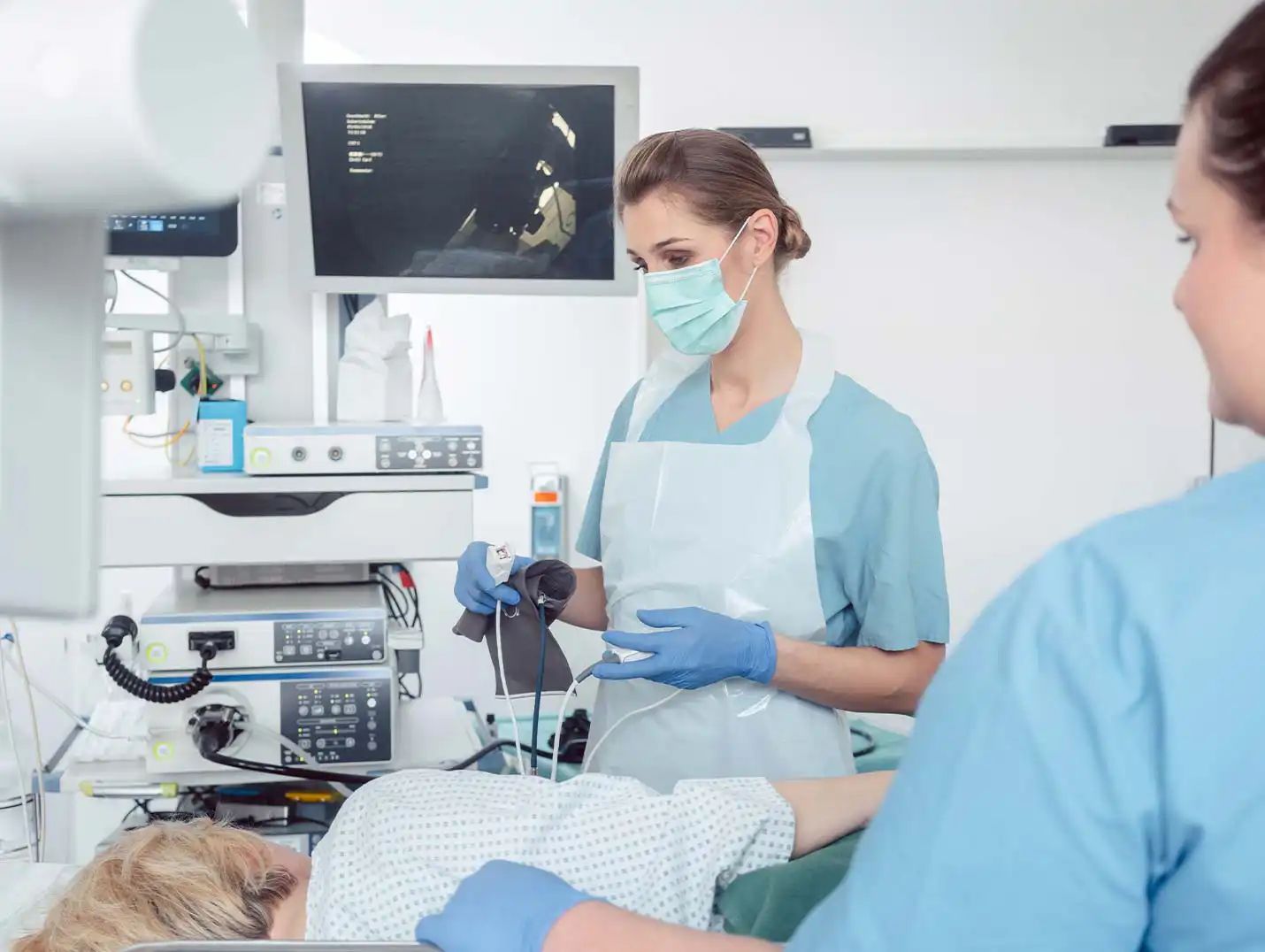 Paciente recostado de lado mientras que unas enfermeras lo preparan para un estudio de fisiologia digestiva.