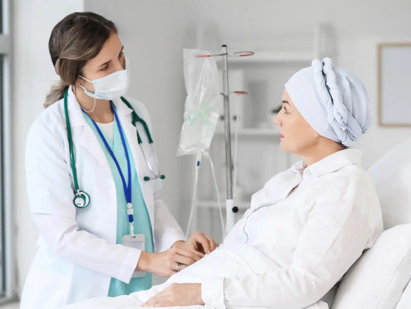 Paciente con cáncer recostada en un cama de hospital mientras escucha atentamente las indicaciones de la doctora