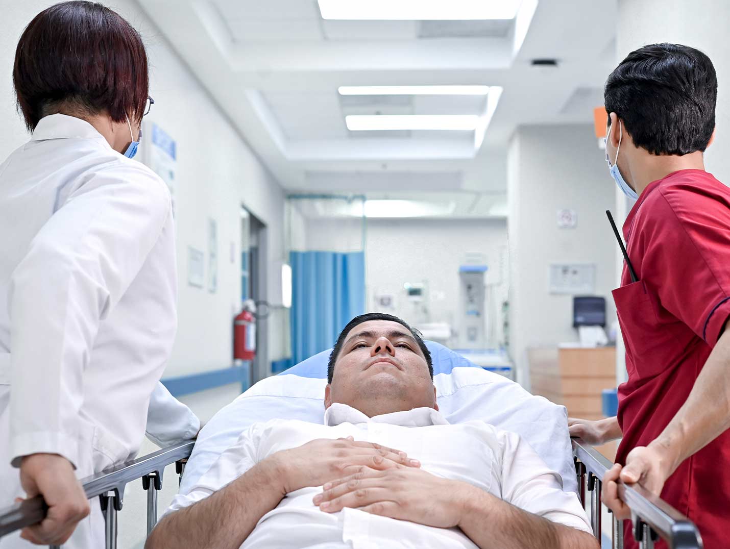Paciente acostado en una camilla mientras una doctora y un enfermero lo llevan al área de urgencias