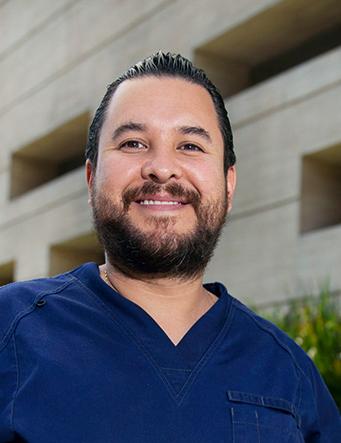 Es la foto de perfil de un ortopedista y traumatólogo en Ciudad de México de Hospital Angeles. El especialista tiene un uniforme azul marino, está sonriendo y tiene barba y bigote.