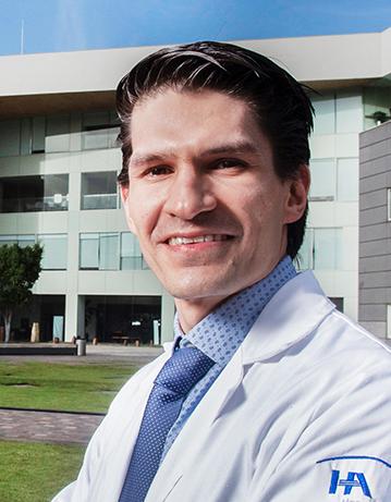 Es la foto de perfil de un internista, hepatolólogo y gastroenterólogo en Ciudad de México de Hospital Angeles. Viste una bata blanca con una camisa azul cielo y una corbata azul rey. Está sonriendo a la cámara, tiene el cabello negro y es de tez blanca. 