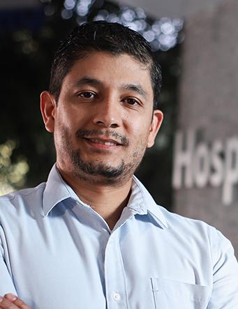 Es la foto de perfil de un cirujano general especialista en gastrocirugía en Huixquilucan de Hospital Angeles Lomas. Tiene los brazos cruzados, está sonriendo, tiene barba y está sonriendo. 