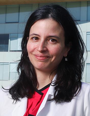 Es la foto de perfil de una oftalmóloga pediátrica en Ciudad de México de Hospital Angeles. Viste una bata con una blusa roja de cuello cerrado color negro. Ella está sonriendo. 