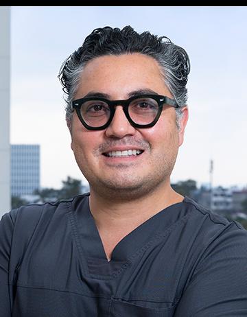 Es la foto de perfil de un cirujano plástico en Ciudad de México de Hospital Angeles Clínica Londres. Utiliza un uniforme médico azul marino y lentes.