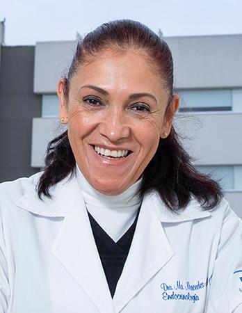 Es la foto de perfil de una endocrinóloga en Ciudad de México de Hospital Angeles Clínica Londres. Utiliza una bata blanca, tiene una blusa blanca debajo de cuello tortuga, su cabello está medio recogido.