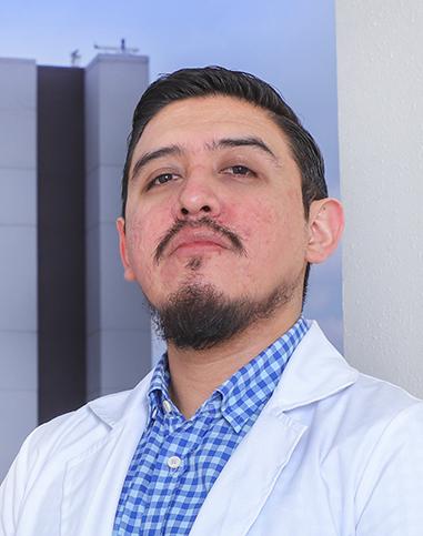 Es la foto de perfil de un infectólogo en Ciudad de México de Hospital Angeles Clínica Londres. Utiliza bata, camisa azul con cuadros y tiene barba y bigote.