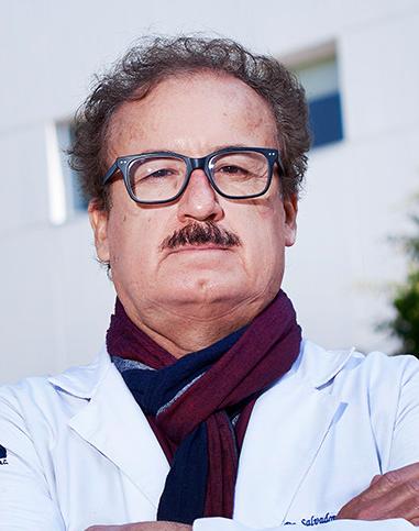 Es la foto de perfil de un cardiólogo en Ciudad de México de Hospital Angeles Lindavista. Tiene el cabello y bigote café. Usa lentes, una bata blanca y una bufanda azul con rojo.