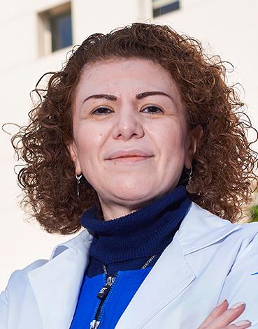 Es la foto de perfil de una reumatóloga en Ciudad de México de Hospital Angeles Lindavista. Tiene el cabello corto, chino y rojizo. Usa una bata blanca y un suéter de cuello alto azul.