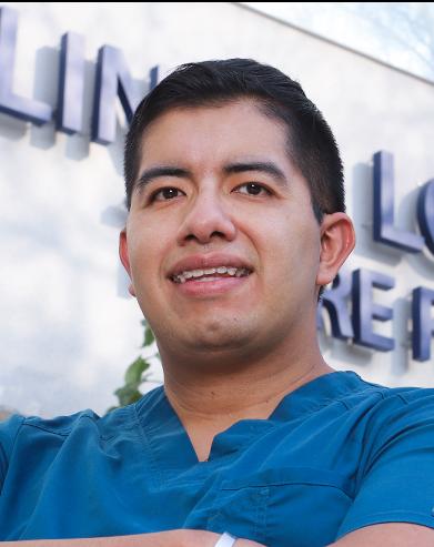 Es la foto de perfil de un gastroenterólogo en Ciudad de México de Hospital Angeles Clínica Londres. Utiliza un uniforme azul, tiene lo brazos cruzados, es de tez morena y cabello oscuro.