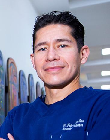 Es la foto de perfil de un neurólogo pediátrico en Ciudad de México. Tiene el cabello negro. Está sonriendo. Usa un uniforme médico azul.