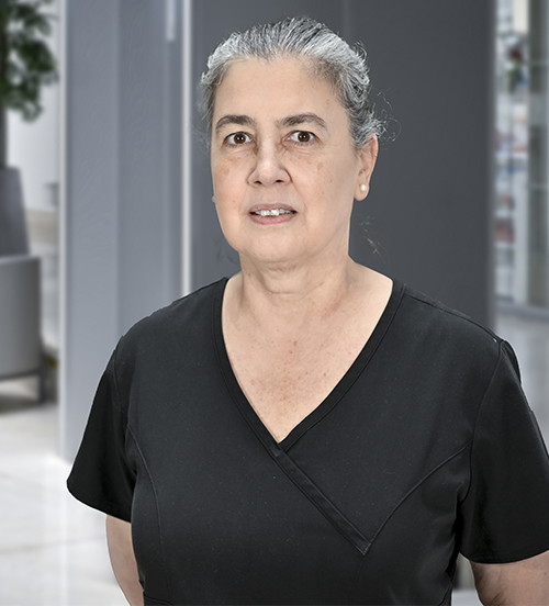 Es la foto de perfil de una cirujana plástica en Huixquilucan. Tiene el cabello gris recogido. Usa un uniforme médico azul.