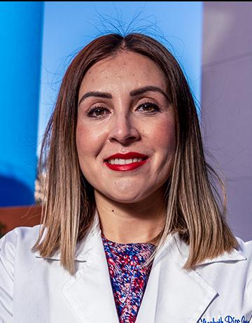 Es la foto de perfil de una hematóloga en Tijuana de Hospital Angeles Tijuana. Usa una bata blanca y blusa con colores morados. Tiene el cabello corto y está sonriendo.