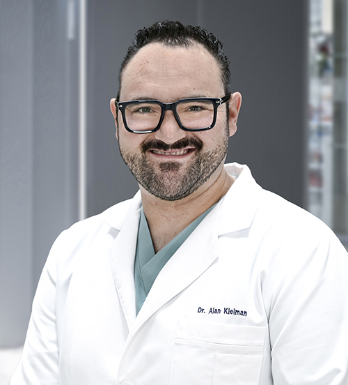 Es la foto de perfil de un cirujano general en Huixquilucan. Tiene el cabello y bigote negro. Usa una camisa azul con cuadros.