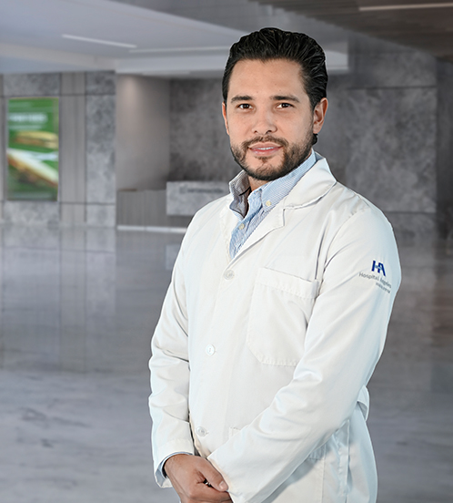 Es la foto de perfil de un ginecólogo y obstetra en Querétaro de Hospital Angeles Centro Sur. Usa un uniforme azul marino, es apiñonado, tiene los brazos cruzados y usa barba.