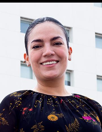 Es la foto de perfil de una oftalmóloga en Ciudad Juárez de Hospital Angeles Ciudad Juárez. Usa una blusa negra con flores de colores, tiene el cabello recogido y está sonriendo.