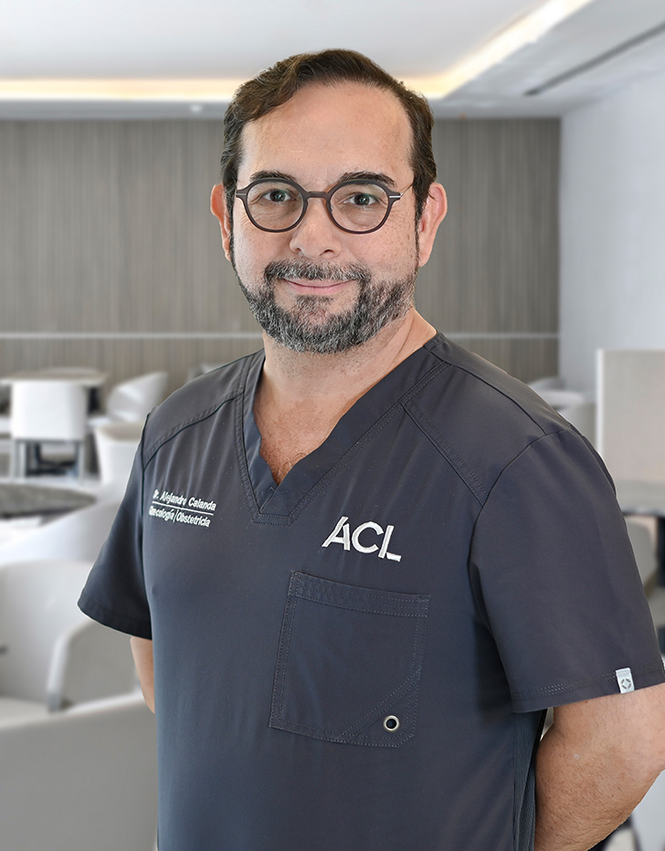 Es la foto de perfil de un ginecólogo y obstetra en San Pedro Garza de Hospital Angeles Valle Oriente. Usa un uniforme médico color azul. Tiene el cabello y barba café oscuro. Tiene los brazos cruzados.