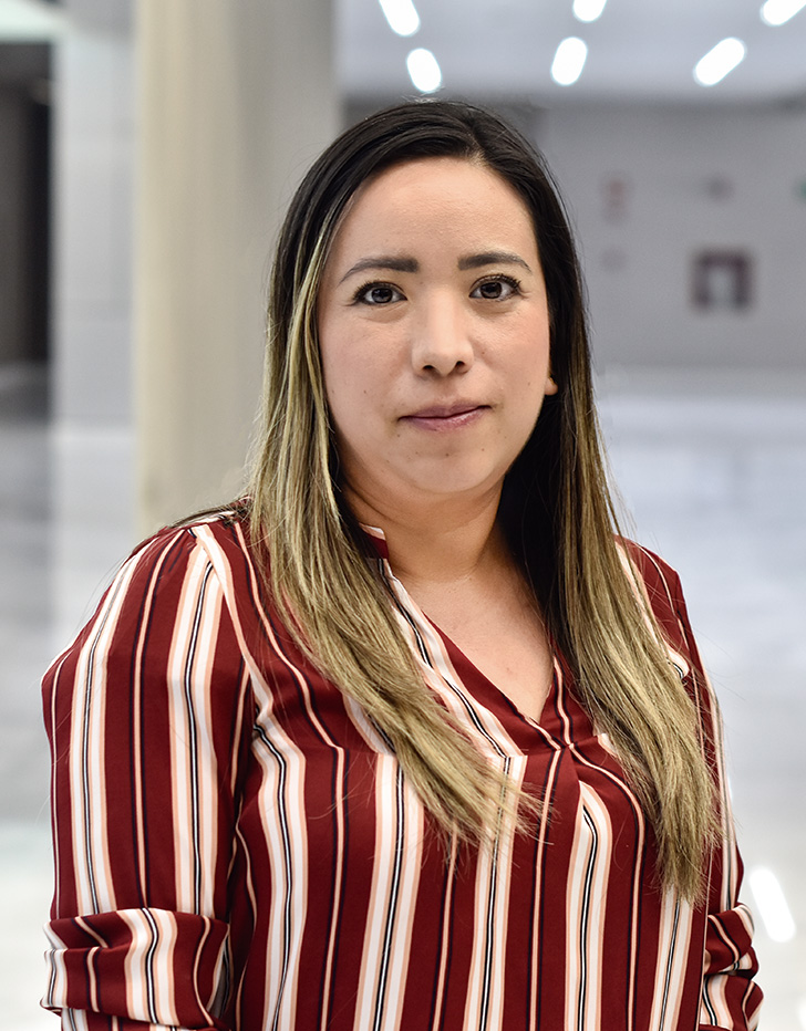 Es la foto de perfil de una cirujana general en Querétaro de Hospital Angeles Centro Sur. Usa una camisa de rayas vino con amarillo y negro, está sonriendo y es de tez morena.