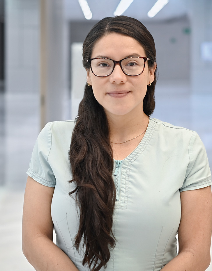 Es la foto de perfil de una hematóloga en Querétaro de Hospital Angeles Centro Sur. Usa una blusa azul cielo sin manga, tiene un collar dorado con perlas pequeñas y su cabello es largo y castaño.