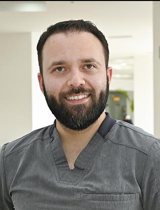 Es la foto de perfil de un otorrinolaringólogo en Ciudad Juárez de Hospital Angeles Ciudad Juárez. Usa un uniforme gris, tiene barba y cabello oscuro.