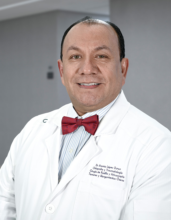 Es la foto de perfil de un ortopedista y traumatólogo pediátrico en Ciudad de México de Hospital Angeles Lindavista. Usa una bata y camisa blanca con un moño azul con estampado.