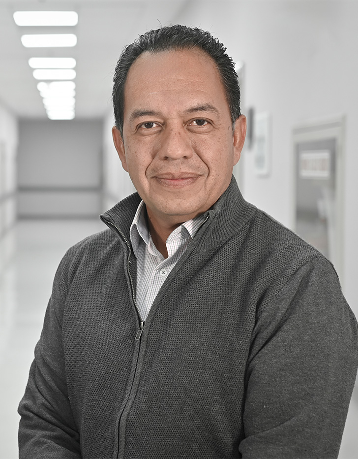 Es la foto de perfil de un cirujano general en Ciudad de México de Hospital Angeles Universidad. Usa un suéter negro y camisa blanca. Está sonriendo.