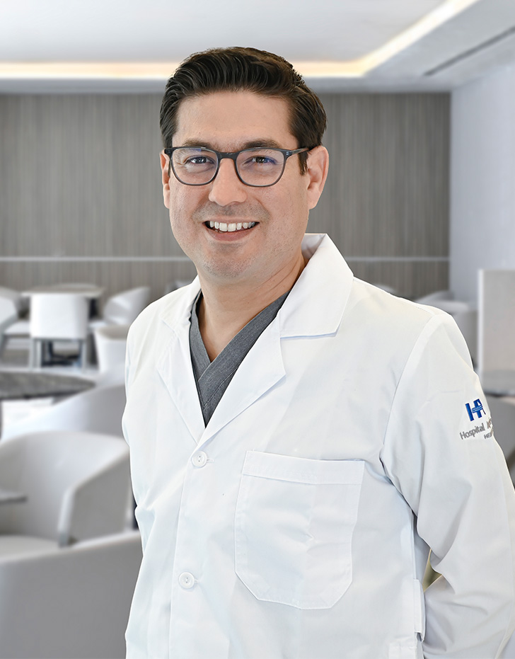Es la foto de perfil de un ortopedista y traumatólogo, especialista en medicina del deporte y artiscopía en San Pedro Garza de Hospital Angeles Valle Oriente. Usa una bata blanca con una corbata gris. Tiene lentes y cabello negro.