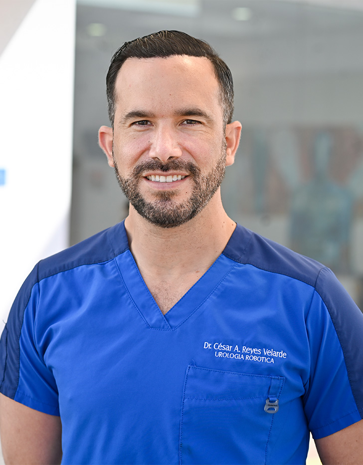 Es la foto de perfil de un urólogo en Tijuana de Hospital Angeles Tijuana. Usa un uniforme médico azul. Tiene el cabello y barba café.