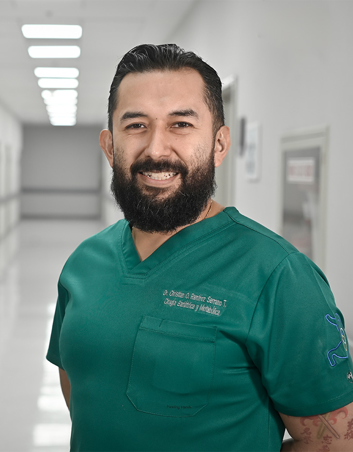 Es la foto de perfil de un cirujano general en Ciudad de México de Hospital Angeles Universidad. Usa un uniforme médico color verde. Tiene el cabello y barba negra.