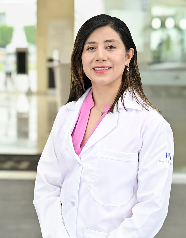Es la foto de perfil de una otorrinolaringóloga en Ciudad de México de Hospital Angeles. Tiene un uniforme de color gris y de fondo se encuentra el hospital.
