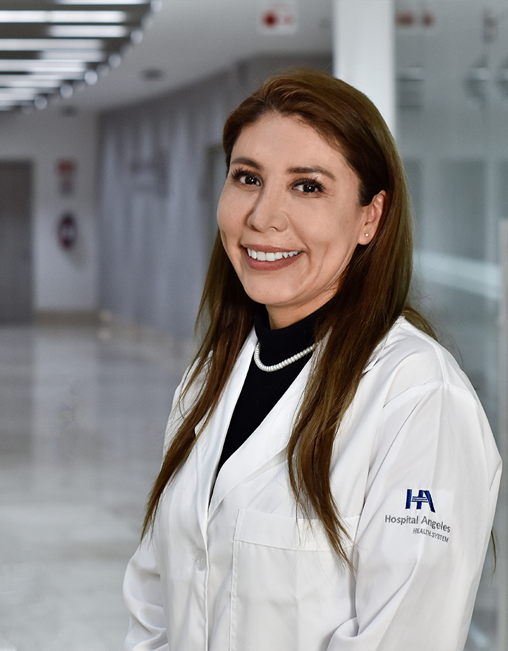 Es la foto de perfil de un pediatra en Huixquilucan de Hospital Angeles Lomas. Usa una bata blanca con un suéter negro con cuello alto, collar de perlas. Tiene cabello largo lacio y está sonriendo.