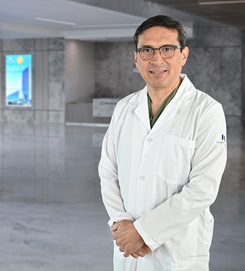 Es la foto de perfil de un ginecólogo y obstetra en Querétaro de Hospital Angeles Centro Sur. Usa una bata blanca, camisa blanca y corbata azul cielo brillante.