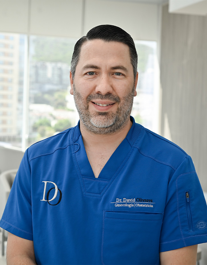 Es la foto de perfil de un ginecólogo y obstetra en San Pedro Garza de Hospital Angeles Valle Oriente. Usa un uniforme médico azul. Tiene el cabello y barba negra.