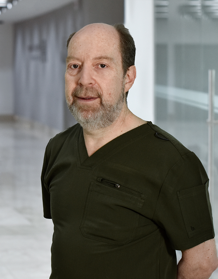 Es la foto de perfil de un pediatra y neonatólogo en Huixquilucan de Hospital Angeles Lomas. Usa un uniforme negro con cuello V, barba canosa y está sonriendo. 