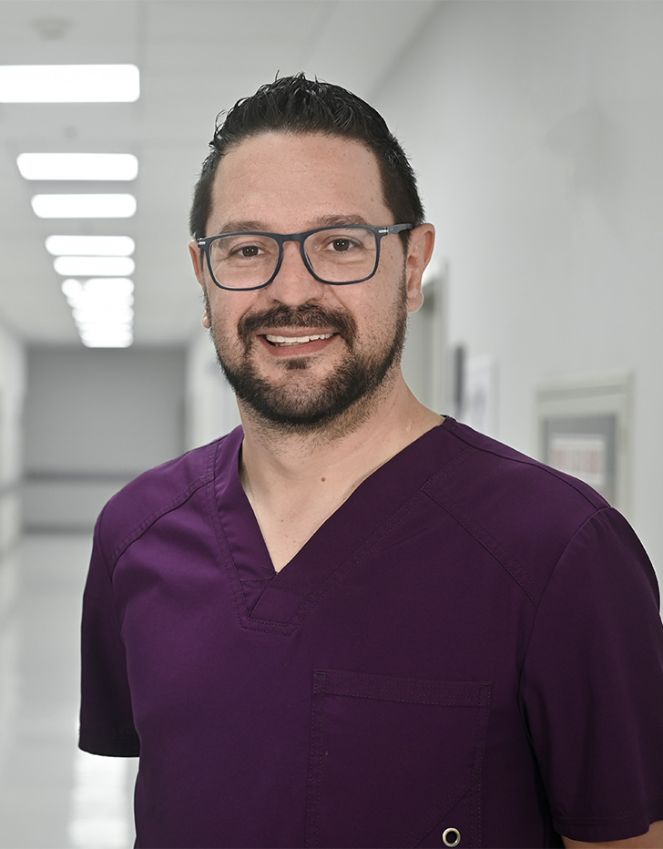 Es la foto de perfil de un otorrinolaringólogo en Ciudad de México de Hospital Angeles Universidad. Usa un uniforme médico color morado y lentes. Tiene el cabello y barba negra.