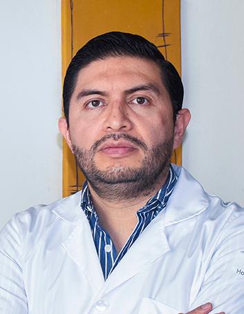 Es la foto de perfil de un médico internista en Xalapa de Hospital Angeles Xalapa. Usa una bata blanca y camisa azul. Tiene el cabello y barba negro.