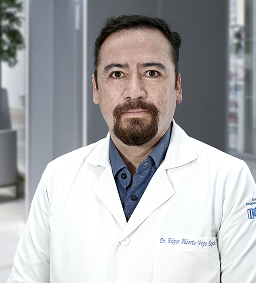 Es la foto de perfil de un ortopedista y traumatólogo en Huixquilucan de Hospital Angeles Lomas. Usa bata blanca con camisa azul fuerte. Tiene los brazos cruzados y está serio.