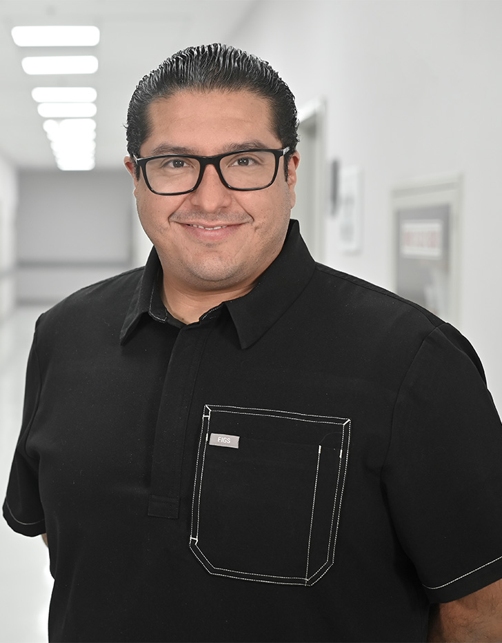 Es la foto de perfil de un neumólogo en Ciudad de México de Hospital Angeles. El doctor tiene un camisa engra de manga corta, está sonriendo y tiene unos lentes cuadrados con el marco negro, está peinado hacia atrás.