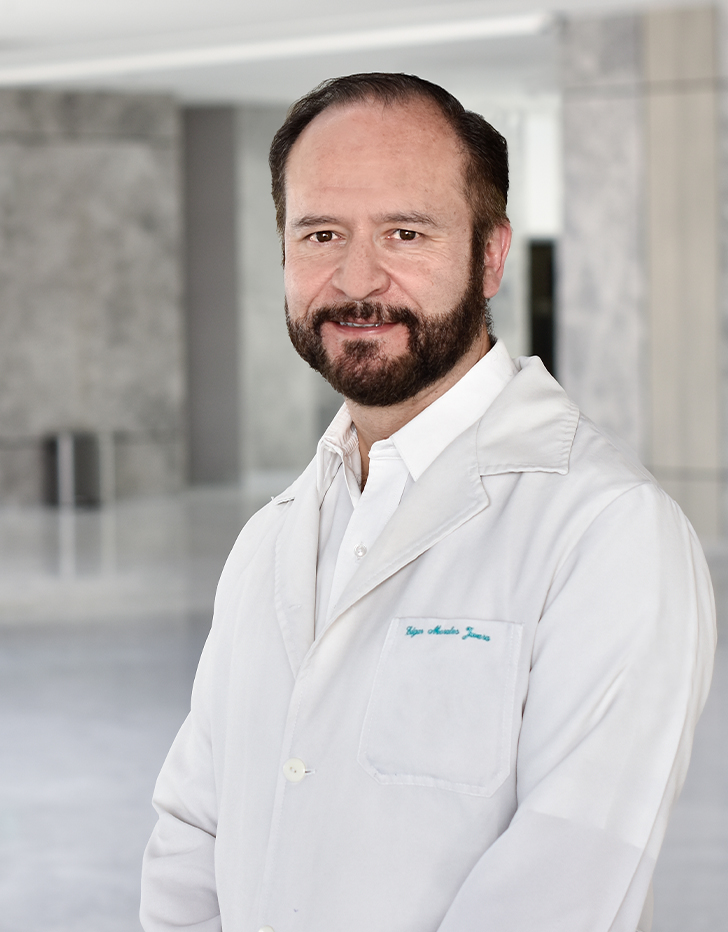 Es la foto de perfil de un urólogo pediátrico en Querétaro de Hospital Angeles Centro Sur. Usa una camisa blanca con una bata blanca, tiene barba y está sonriendo.